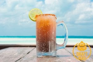 "Michelada" beer jar with a lemon slice on a blue sky with clouds